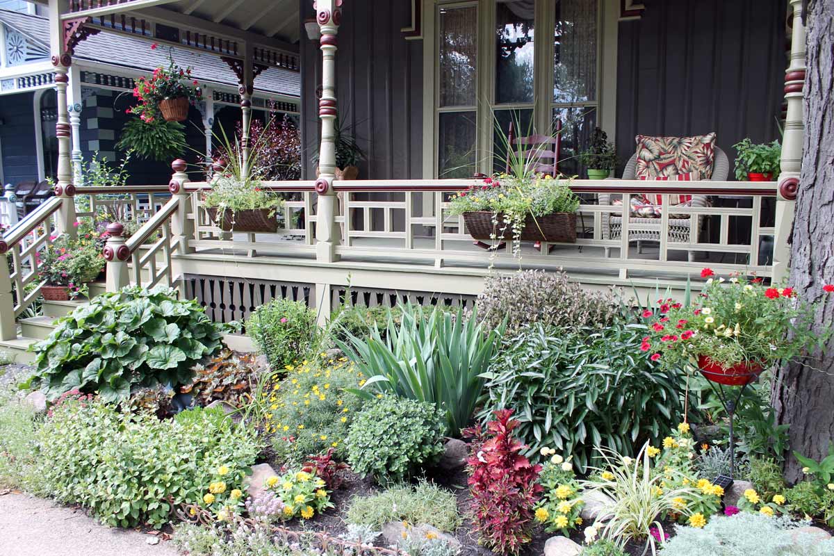 Small flower bed with compact shrubs along the front of a front porch.